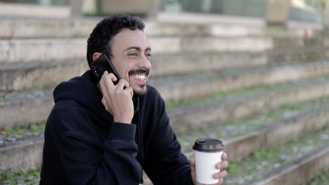 Lächelnder-Mann-Mit-Kaffee-Zum-Mitnehmen,-Der-Sich-Per-Smartphone-Unterhält